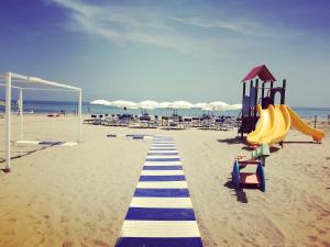 a playground on the beach with chairs and umbrellas at Hotel Florida in Silvi Marina