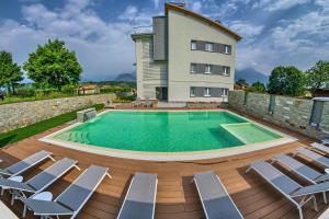 einen Pool mit Stühlen und ein Gebäude in der Unterkunft Rainbow Holiday Apartments Lake Como in Colico