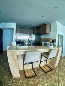 a kitchen with a large wooden counter with two chairs at Condado Beachfront- Perfect for Families! in San Juan +21 photos