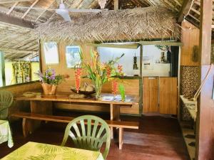 a dining room with a wooden table and chairs at HUAHINE - Bungalow Picasso in Fare