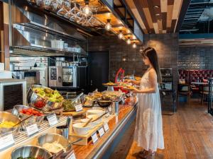 a woman standing in a kitchen preparing food at Hotel Cocktail Stay Naha in Naha