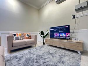 a living room with a couch and a large television at Vintage-Living 2Storey Haus12Pax in Simpang Ampat