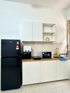 a kitchen with a black refrigerator and white cabinets at Vintage-Living 2Storey Haus12Pax in Simpang Ampat