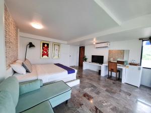 a bedroom with a bed and a couch and a desk at Tawanja Resort in Ban Mai