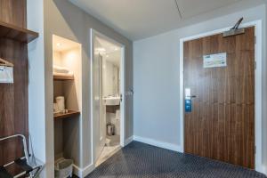a hallway with a wooden door and a bathroom at Holiday Inn Express Aberdeen Airport by IHG in Dyce