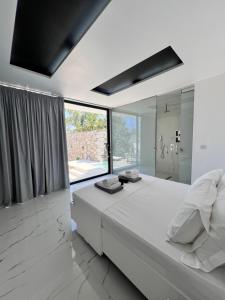 a white bedroom with a large bed and a large window at Private Pool House for 6 by Olivujoj in Anavyssos +35 photos