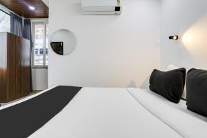 a bedroom with a white bed with black pillows at Collection O De Alphabet Hotel in Hyderabad +34 photos