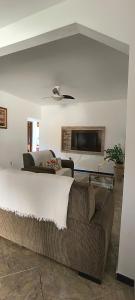 a bedroom with a bed and a couch and a tv at CasaPraiaSol1 in Rio das Ostras