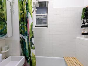 een badkamer met witte tegels en een douchegordijn bij Union Square Sanctuary - Chic One Bedroom Retreat in Downtown Manhattan in New York +12 foto's