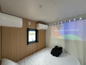 a small room with a bed with a black bag on it at Flatonia Glamping Retreat - Musk Tiny House - Unique Container Cabin in Flatonia
