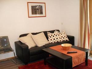 ein Wohnzimmer mit einem schwarzen Sofa und einem Tisch in der Unterkunft Heulandhof in Bad Hindelang