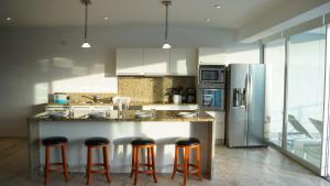 a kitchen with a island with bar stools and a refrigerator at Magia Beachside Apartment by BVR in Playa del Carmen