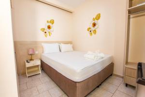 a small bedroom with a bed and two flowers on the wall at Psarotherma Rooms in Samothraki