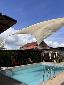 a swimming pool with a tan umbrella over it at Sand Dune Villa in Kampong Beting Lintang
