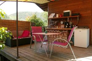 a patio with a table and chairs on a deck at le refuge des pots rouges in Cros