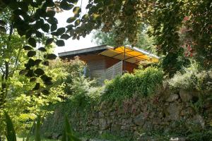 a house with a yellow umbrella behind a stone wall at le refuge des pots rouges in Cros +13 photos