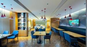 un restaurante con sillas y mesas azules y TV en Borrman Hotel Zhanjiang Xuwen Port Terminal, en Xuwen