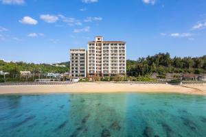 a large building on a beach with a body of water at Best Western Okinawa Kouki Beach in Nago