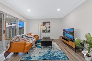 a living room with a couch and a tv at KozyGuru | Austral | 5 Bed Comfy House in Horningsea Park