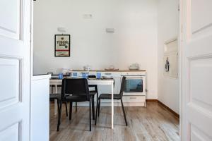 a white kitchen with a table and black chairs at Giosue' Apartment Near Bari - Happy Rentals in Adelfia