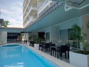 an outdoor swimming pool with tables and chairs and a building at Chequers Suites Subic Bay in Olongapo