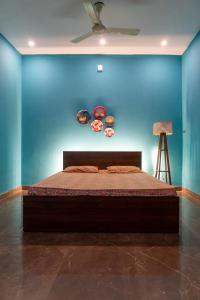 une chambre avec un lit avec un mur bleu dans l'établissement Garden cottage, 5 mins from Isha Yoga Center, à Alāndurai