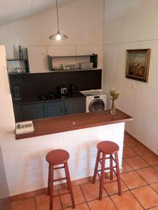 a kitchen with a counter with two stools and a microwave at La kaz de l'arbre voyageur in LʼEntre-Deux