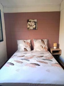 a bedroom with a bed with a white comforter at La kaz de l'arbre voyageur in LʼEntre-Deux