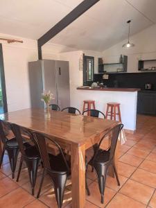 a wooden table with black chairs and a kitchen at La kaz de l'arbre voyageur in LʼEntre-Deux