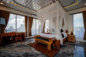 a bedroom with a canopy bed and a desk at Grand Campuhan in Tegalalang