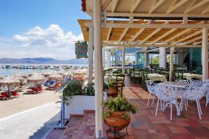 a patio with tables and chairs on the beach at Aktaion Beach Boutique Hotel & Spa in Skala