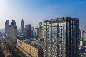 a tall building in a large city with buildings at Meijin All Suites Hotel Suzhou in Suzhou