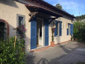 une maison avec volets bleus et terrasse couverte dans l'établissement Il Giardino segreto Forte dei Marmi, à Forte dei Marmi