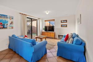 ein Wohnzimmer mit 2 blauen Sofas und einem TV in der Unterkunft Pelican Cottage in Dunsborough