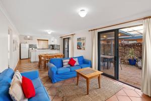 ein Wohnzimmer mit einem blauen Sofa und einem Tisch in der Unterkunft Pelican Cottage in Dunsborough