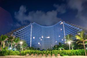 a large building with palm trees in front of it at Arena Seaview Apartment - Cam Ranh Resort in Cam Ranh International Airport