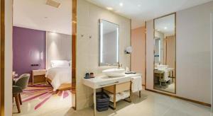 a bedroom with a bed and a sink and a mirror at Lavande Hotel Wuhan Houhu Avenue Xingye Road in Wuhan +230 photos