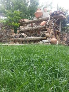 a yard with grass and a stone building with a stone bench at Uysallar Koy Evi in Gokceada Town