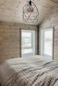 a bedroom with a bed and two windows at Mountain Cabin With Glacier Views in Norheimsund