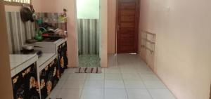 a kitchen with a white tiled floor and a door at Veni Homestay in Batukaras