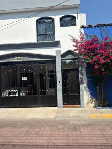 a building with black doors and pink flowers at Estancia Colobri in Guadalajara