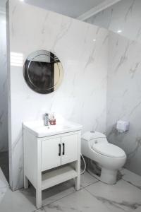 a white bathroom with a toilet and a mirror at GIRLAN Homestay in Ngabean +17 photos