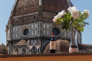 - une bouteille de vin, 2 verres et un vase de fleurs dans l'établissement Era Rental Apartments, à Florence
