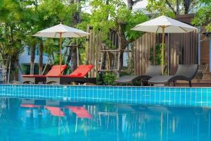 a swimming pool with chairs and umbrellas next to a pool at Chatnipa Beach Resort in Rayong