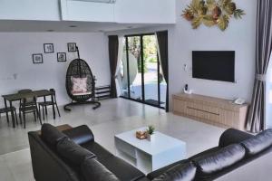 a living room with a couch and a tv and a table at Chatnipa Beach Resort in Klaeng
