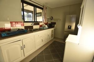 a kitchen with white cabinets and a refrigerator at Maison LE GLAS in Curepipe