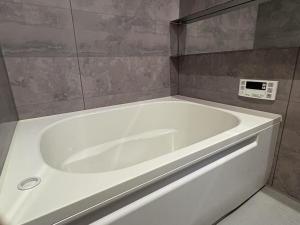 a white bath tub in a bathroom with a tile wall at 東福寺2 都憶 in Kyoto +28 photos