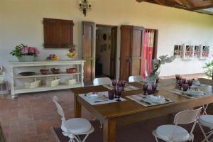 a dining room with a wooden table and white chairs at Villa Ines with pool and Jacuzzi hot tube in Terranuova Bracciolini