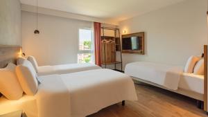 a hotel room with two beds and a window at KYRIAD DAX - Saint Paul lès Dax in Saint-Paul-lès-Dax