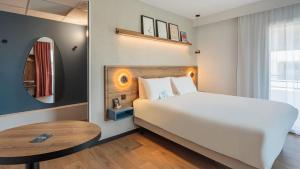 a bedroom with a white bed and a table at KYRIAD DAX - Saint Paul lès Dax in Saint-Paul-lès-Dax